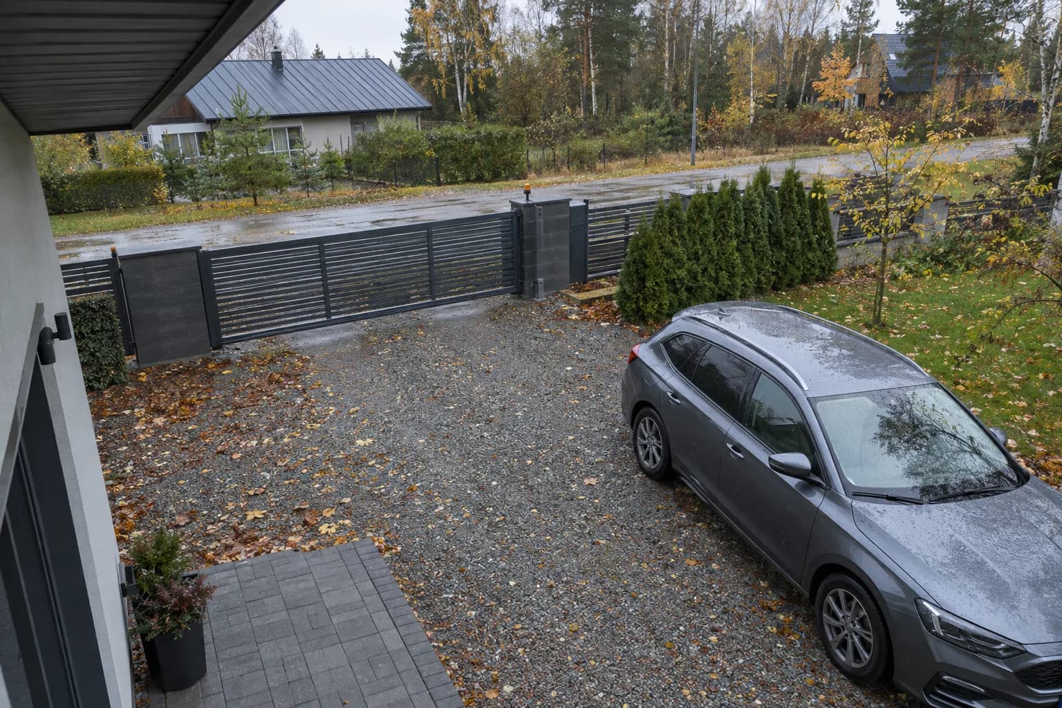 Vaade räästa alt eramaja sissesõiduteele, suletud väravale ja pargitud autole